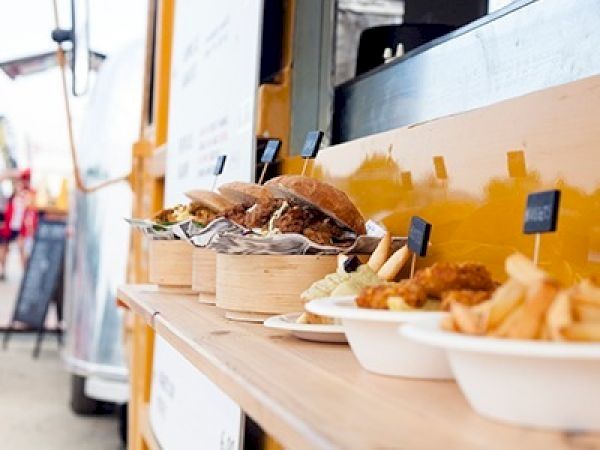 A food truck setup with a sandwich and sides on a counter, served in disposable containers.