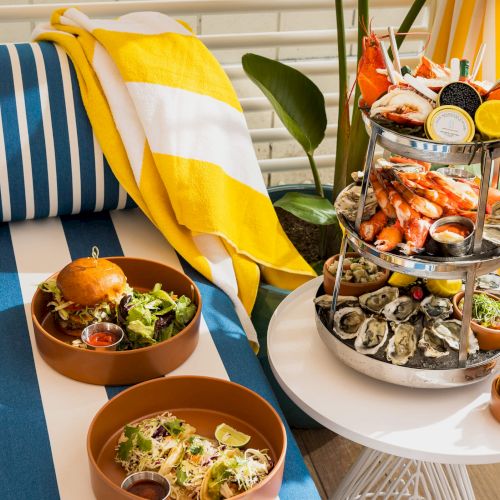 A colorful assortment of packaged snacks and a small dessert on a wooden table.