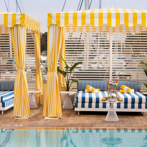 Two vintage beige crates filled with small blue and brown birds inside, perched on a shelf; sunlight glints off their beaks and the scene feels rustic.