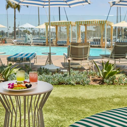 Cheerful outdoor cafe on a sunny beach, white tablecloths, wicker chairs, and a turquoise sea in the background.